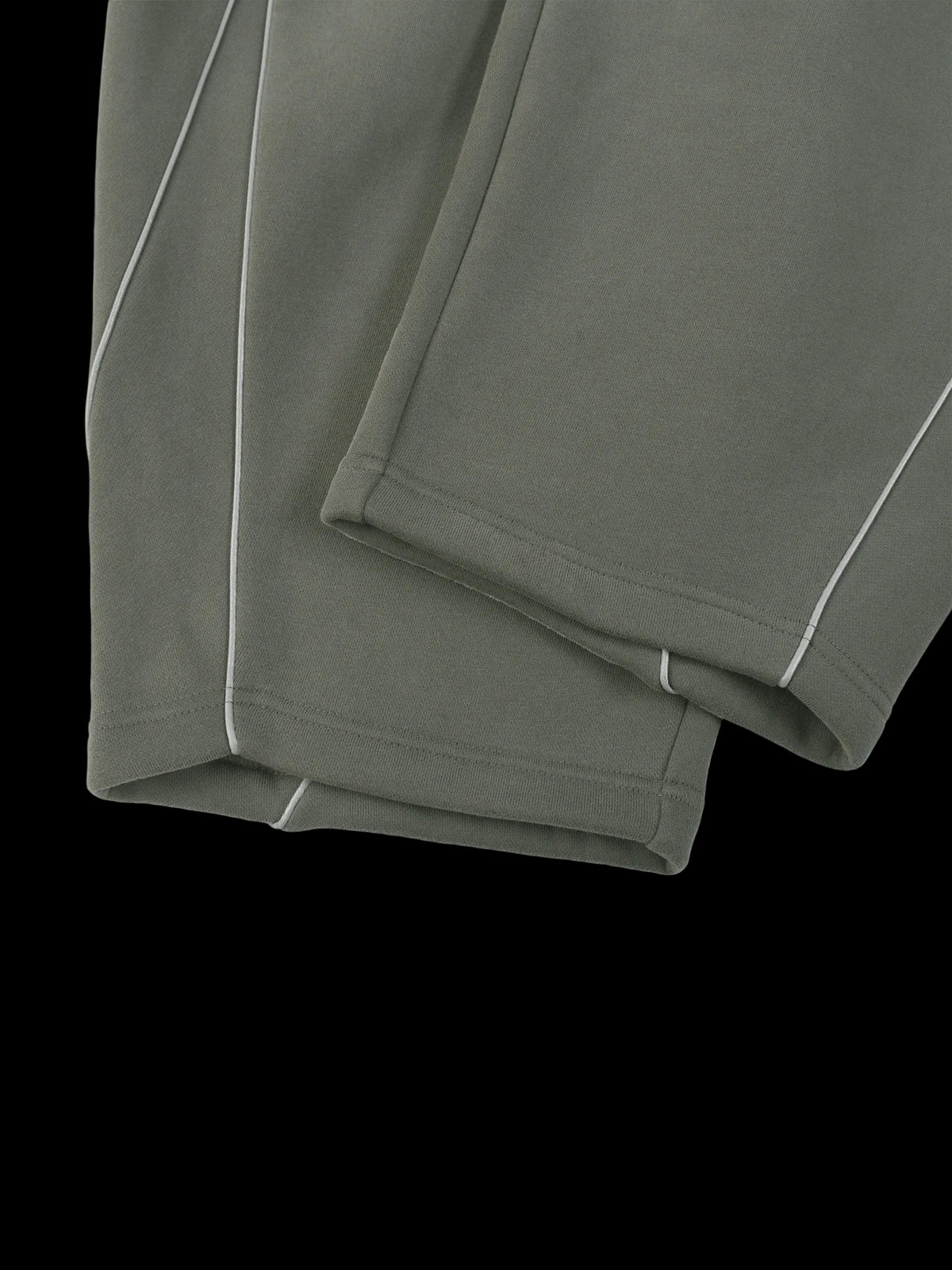 Close-up of folded olive green fabric with thin white contrast stitching along the edges, shown on a plain white background.
