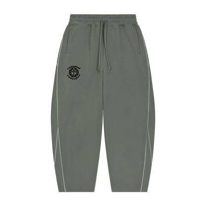 Olive green jogger-style pants with a black embroidered compass logo on the left chest, white piping along the outer sides, and a drawstring waistband, shown against a plain white background.