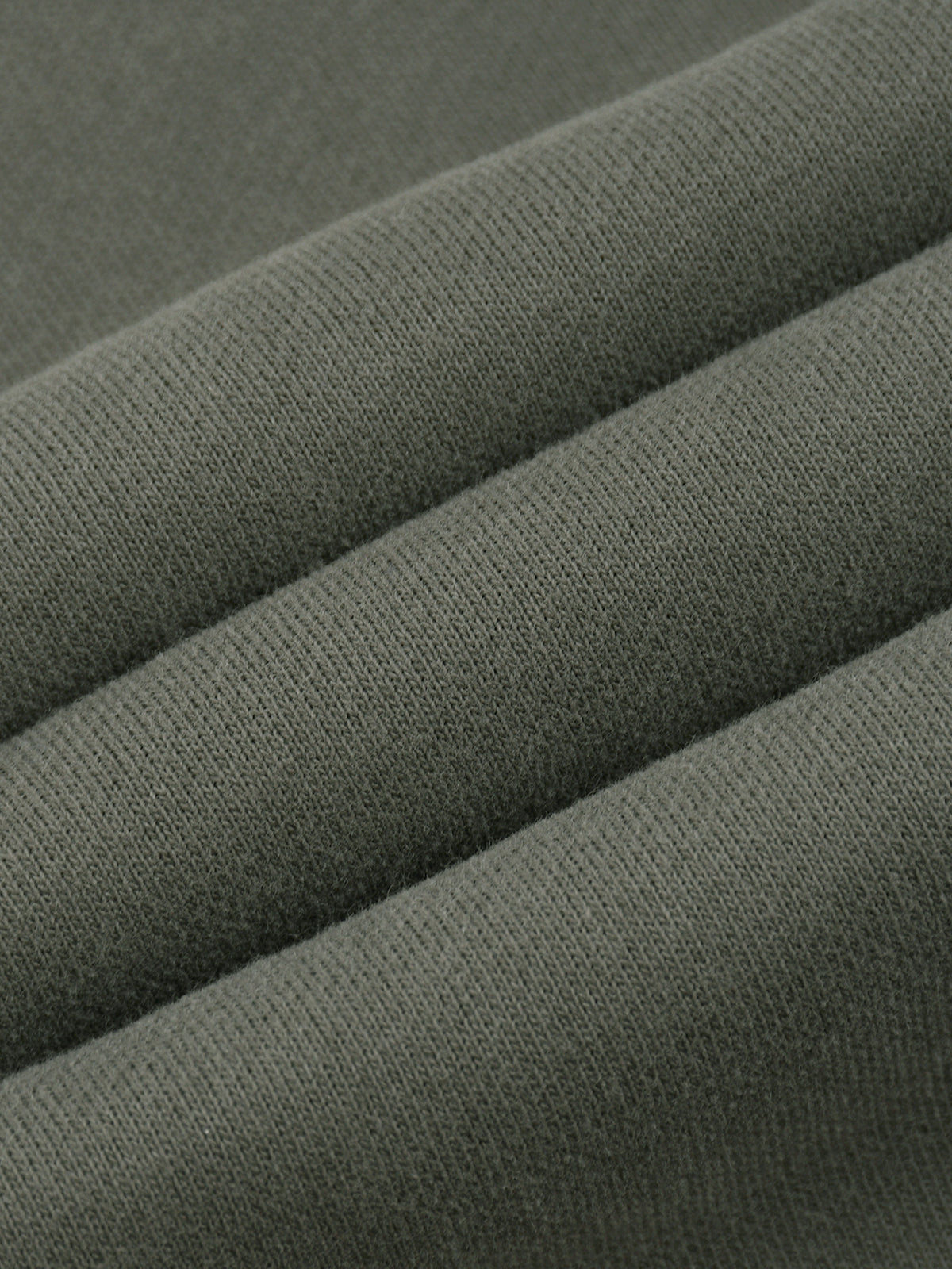 A close-up of folded olive green knit fabric showing the texture and weave.
